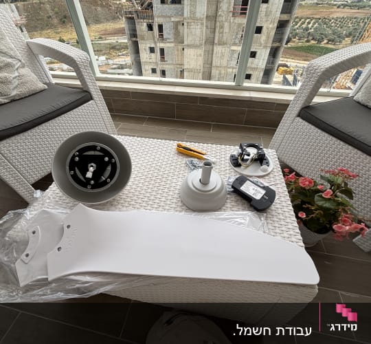 חלקי מאוורר על שולחן במרפסת עם נוף לבניין בבנייה